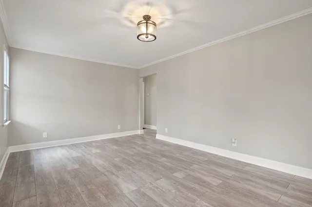a view of an empty room with wooden floor and ceiling fan