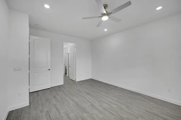 an empty room with wooden floor and ceiling fan