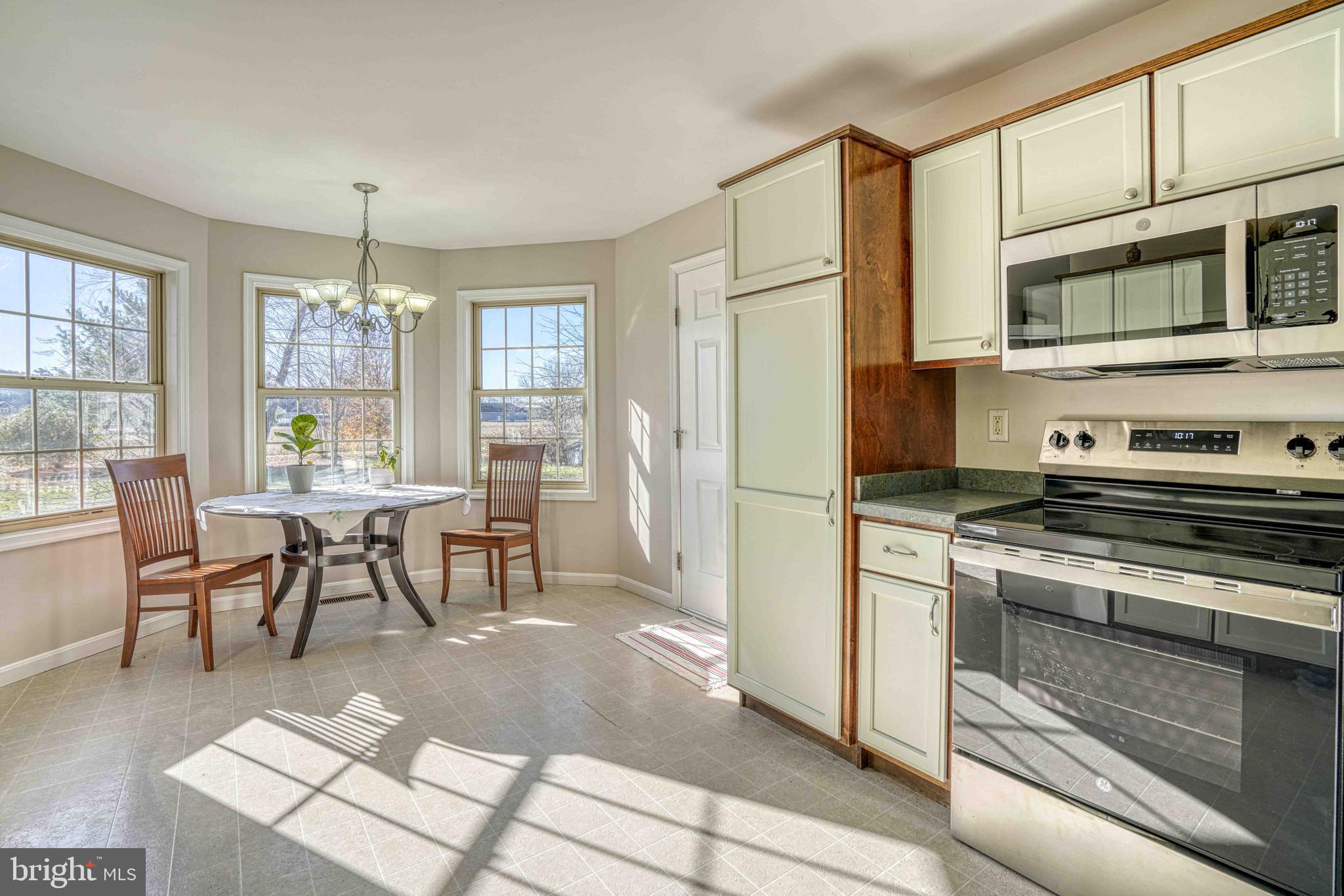 36620 Robin Hood Road Delmar, DE 19940 - Photo 11 of 48 a kitchen with stainless steel appliances granite countertop a stove top oven a refrigerator a dining table and chairs with wooden floor