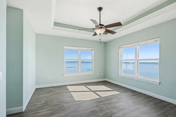 an empty room with wooden floor chandelier and windows