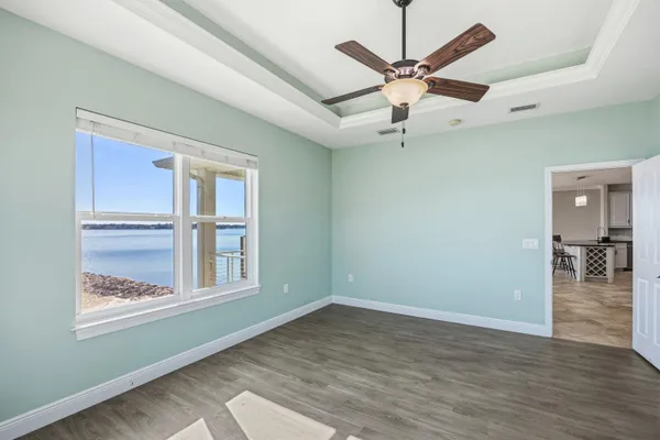 an empty room with wooden floor fan and windows