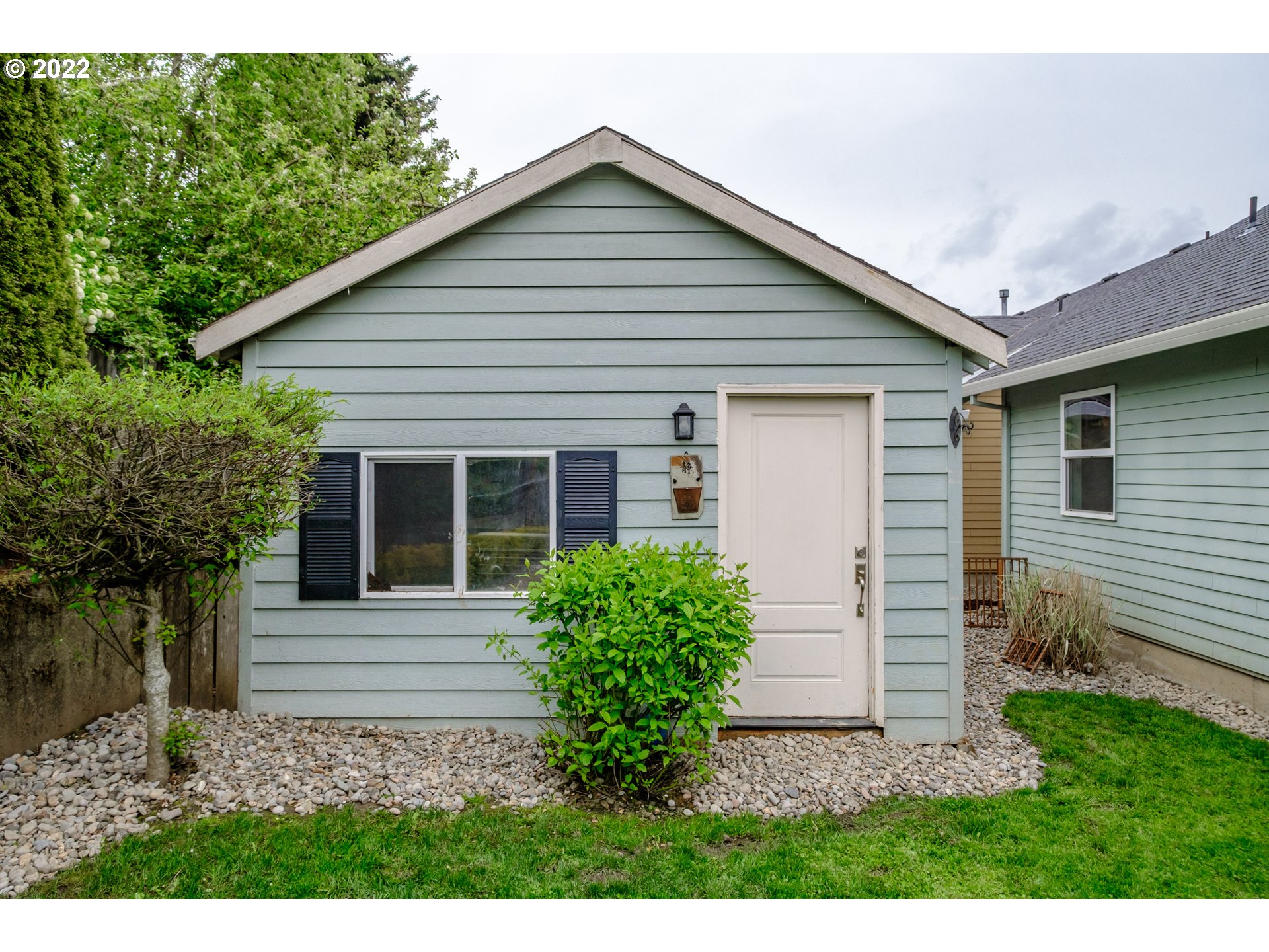3778 10th Street Hubbard, OR 97032 - Photo 31 of 32 a view of a house with brick walls and a yard with plants and a large tree