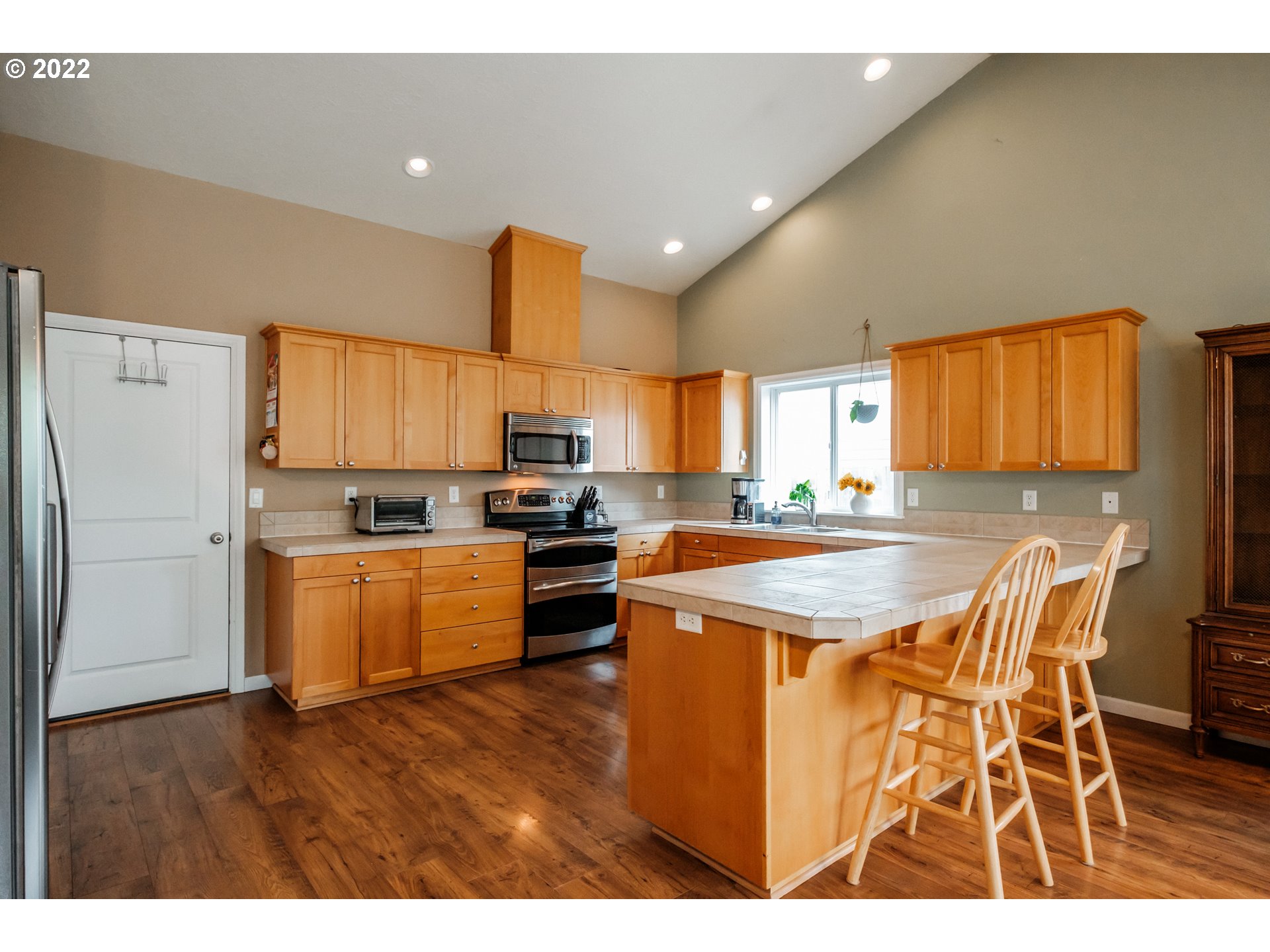 3778 10th Street Hubbard, OR 97032 - Photo 9 of 32 a kitchen with stainless steel appliances kitchen island granite countertop a refrigerator a stove a sink dishwasher with a dining table and chairs
