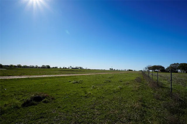 a view of a field with an ocean and trees