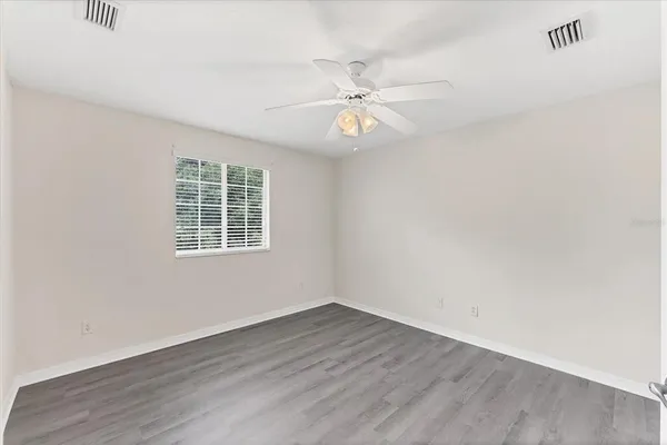 an empty room with wooden floor and ceiling fan