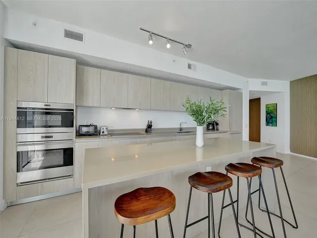 a kitchen with stainless steel appliances a table and chairs in it