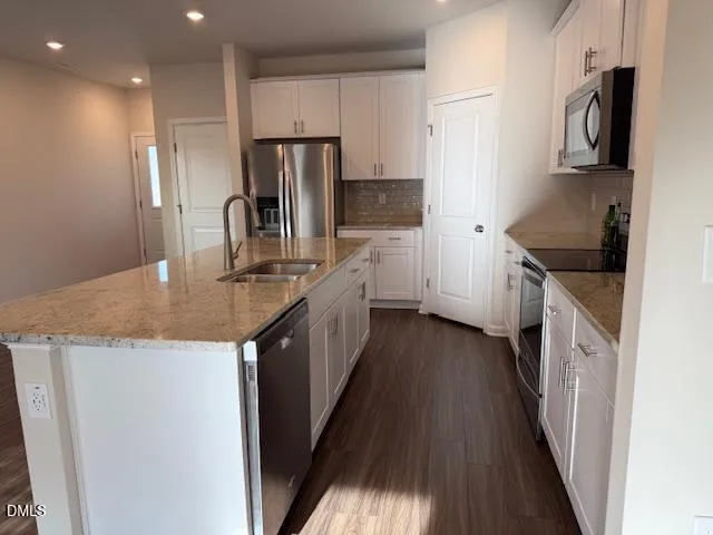 a kitchen with kitchen island granite countertop a sink a counter top space stainless steel appliances and cabinets