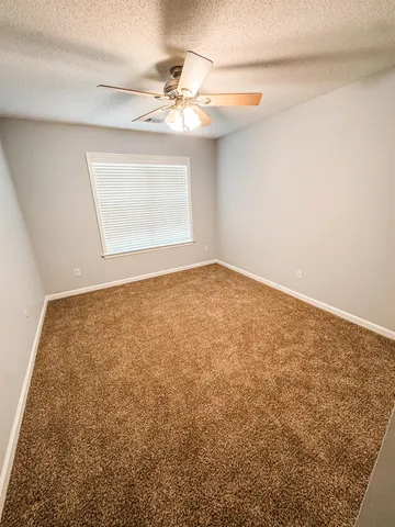 en empty room with window and chandelier fan