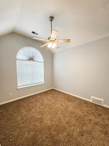 a view of an empty room with window and chandelier fan