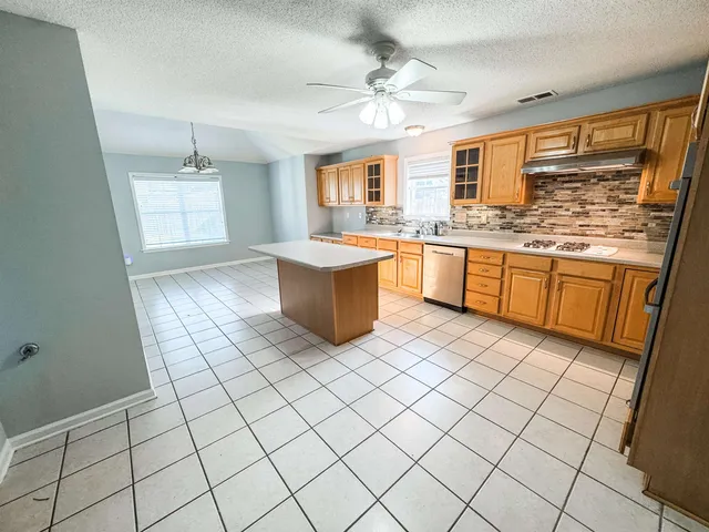 a large white kitchen with a stove a sink dishwasher and a refrigerator