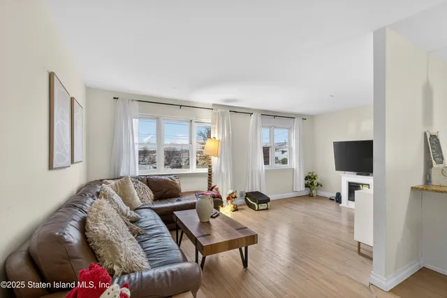 a view of a livingroom with a flat screen tv a ceiling fan and windows
