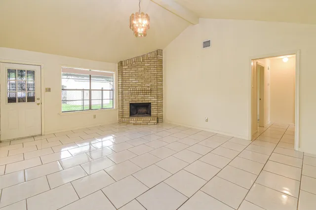 an empty room with windows and fireplace