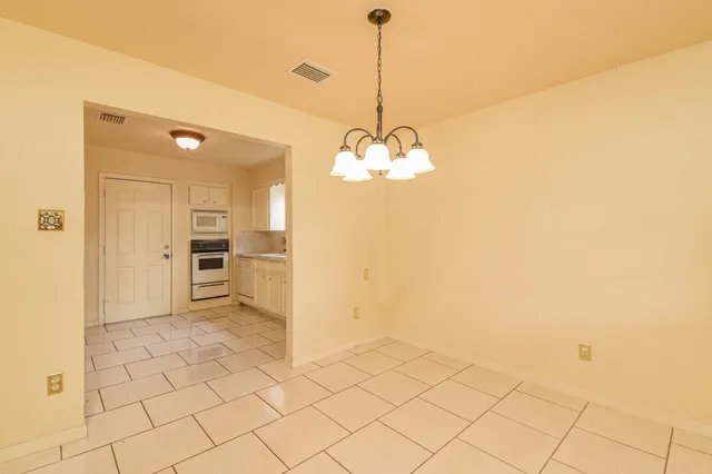 a view of a room with a chandelier fan and kitchen view