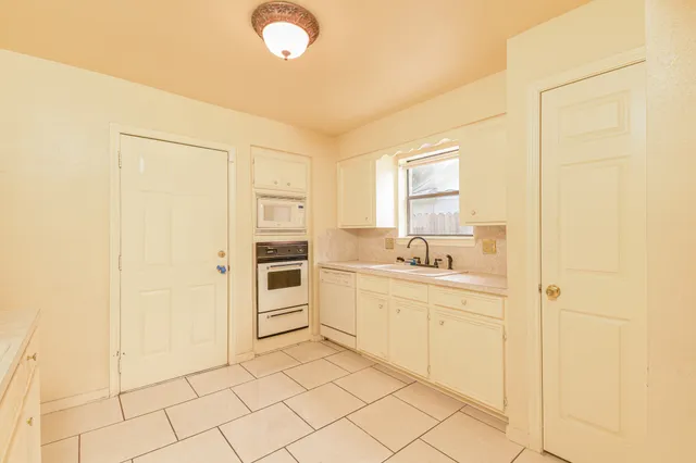 a kitchen with white cabinets and white appliances