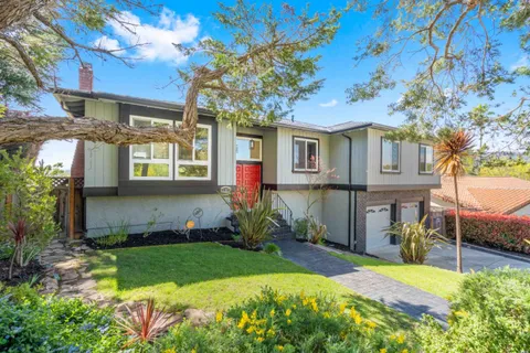 a front view of a house with a yard and potted plants