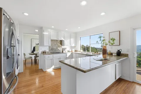 a kitchen with granite countertop white cabinets and stainless steel appliances