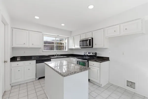 a kitchen with granite countertop a sink stove and cabinets