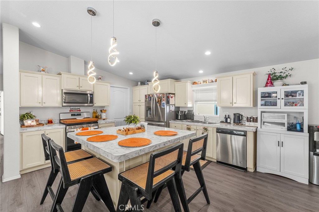 4901 Green River Road, Unit 96 Corona, CA 92878 - Photo 13 of 35 a kitchen with stainless steel appliances kitchen island granite countertop a dining table and chairs