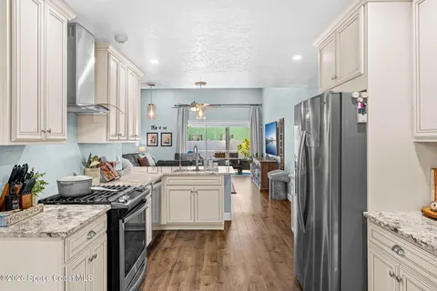 a kitchen with stainless steel appliances granite countertop a refrigerator stove sink and cabinets