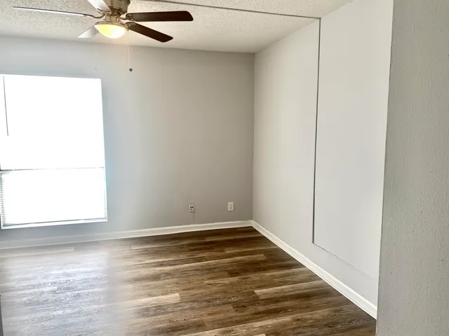 a view of a room with wooden floor and a ceiling fan