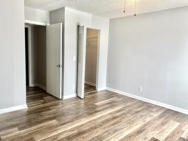 a view of an empty room with wooden floor and a bathroom