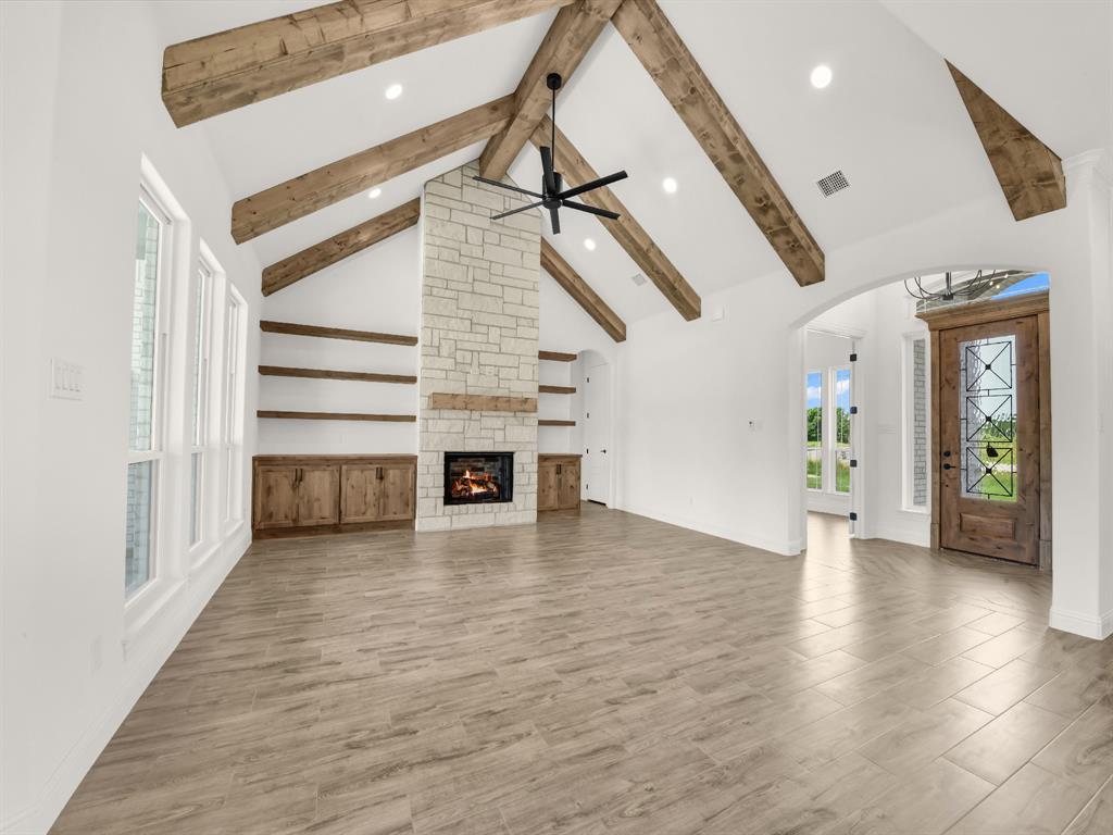143 Desperado Way Weatherford, TX 76088 - Photo 17 of 36 Unfurnished living room with beamed ceiling, wood finished floors, recessed lighting, plenty of natural light, and arched walkways