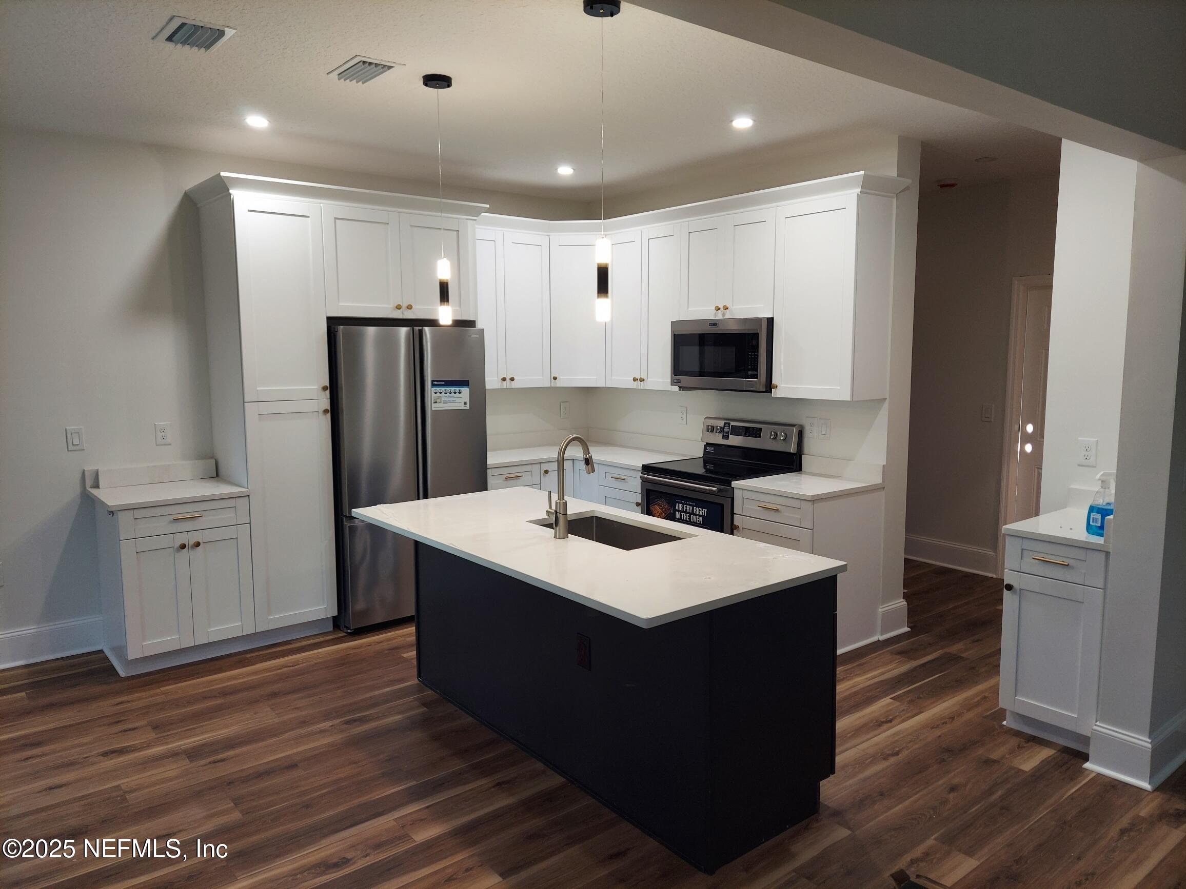 1337 Roxie Street Atlantic Beach, FL 32233 - Photo 3 of 6 a kitchen with kitchen island a sink stainless steel appliances and cabinets