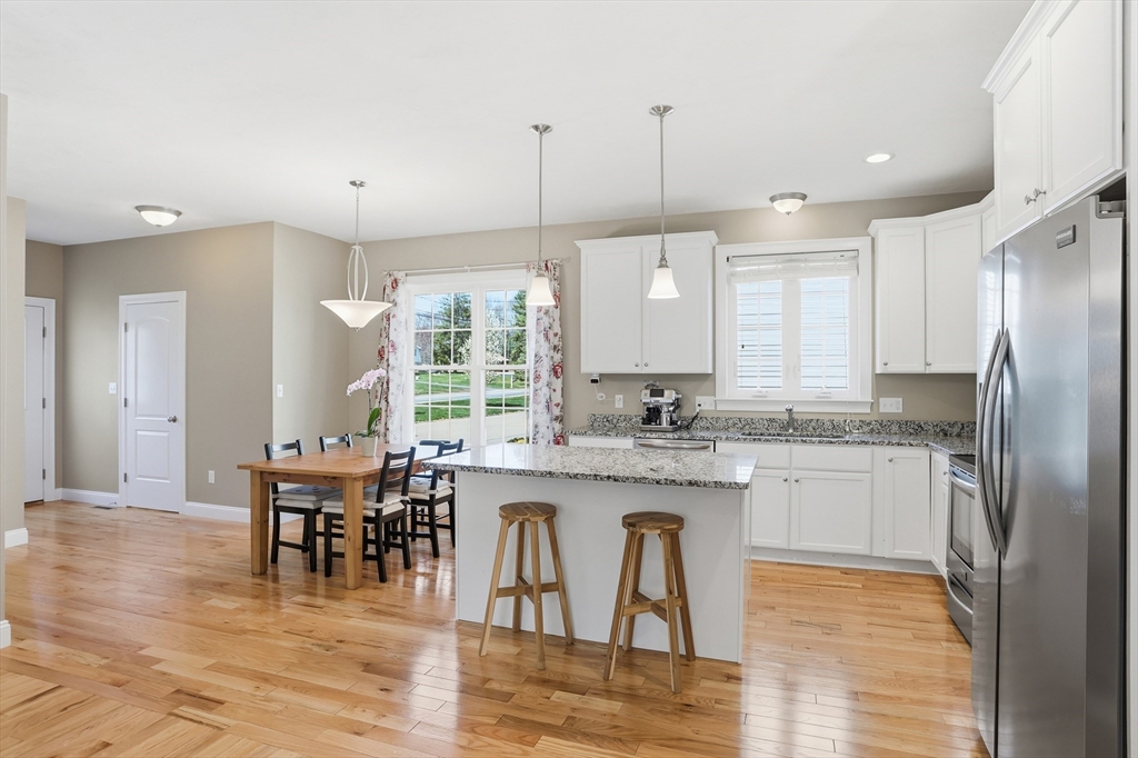 2 Dino Way, Unit 52 Milford, MA 01757 - Photo 11 of 41 a kitchen with stainless steel appliances granite countertop a table chairs stove a sink and dishwasher