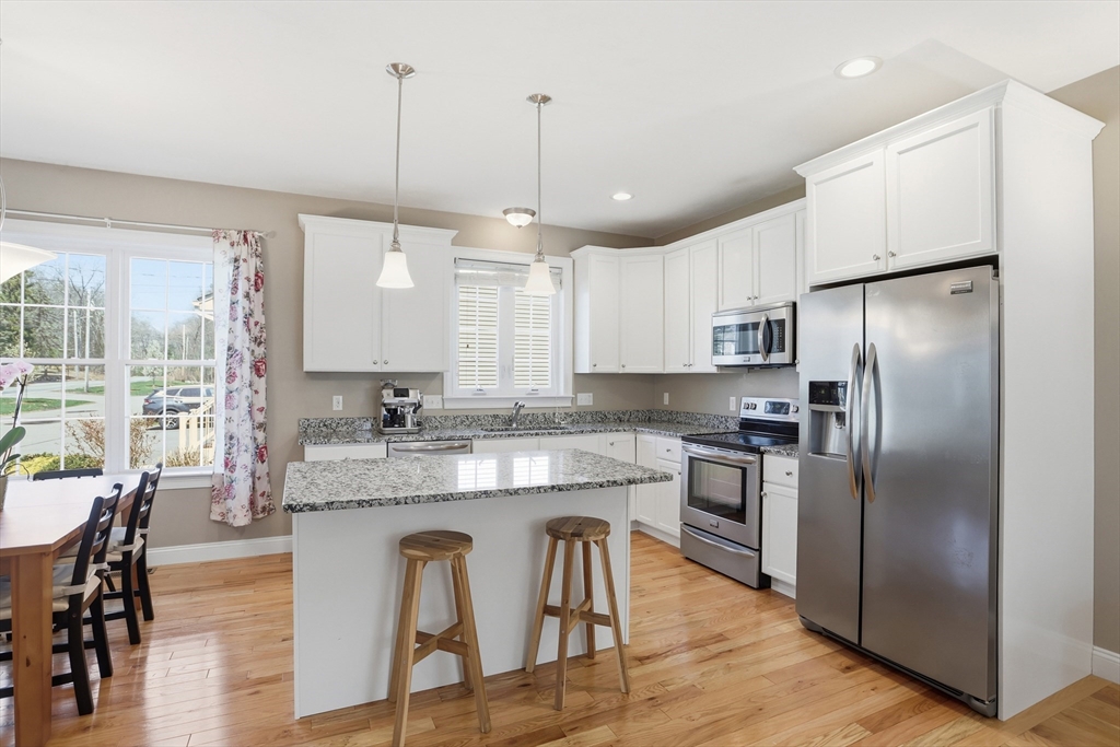 2 Dino Way, Unit 52 Milford, MA 01757 - Photo 14 of 41 a kitchen with stainless steel appliances granite countertop a refrigerator a sink dishwasher a stove and white cabinets with wooden floor