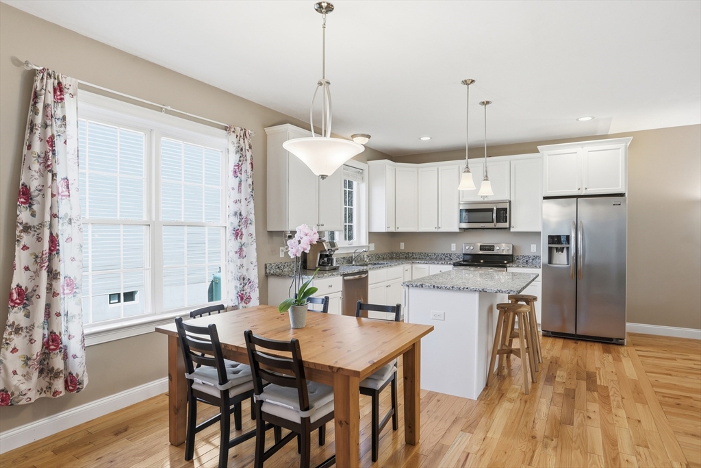 2 Dino Way, Unit 52 Milford, MA 01757 - Photo 15 of 41 a kitchen with stainless steel appliances kitchen island granite countertop a table chairs and a refrigerator