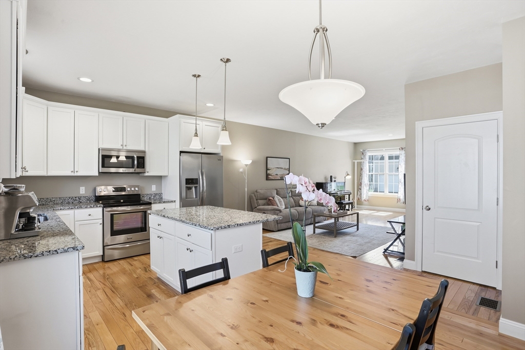 2 Dino Way, Unit 52 Milford, MA 01757 - Photo 16 of 41 a living room with stainless steel appliances kitchen island granite countertop furniture and a wooden floor
