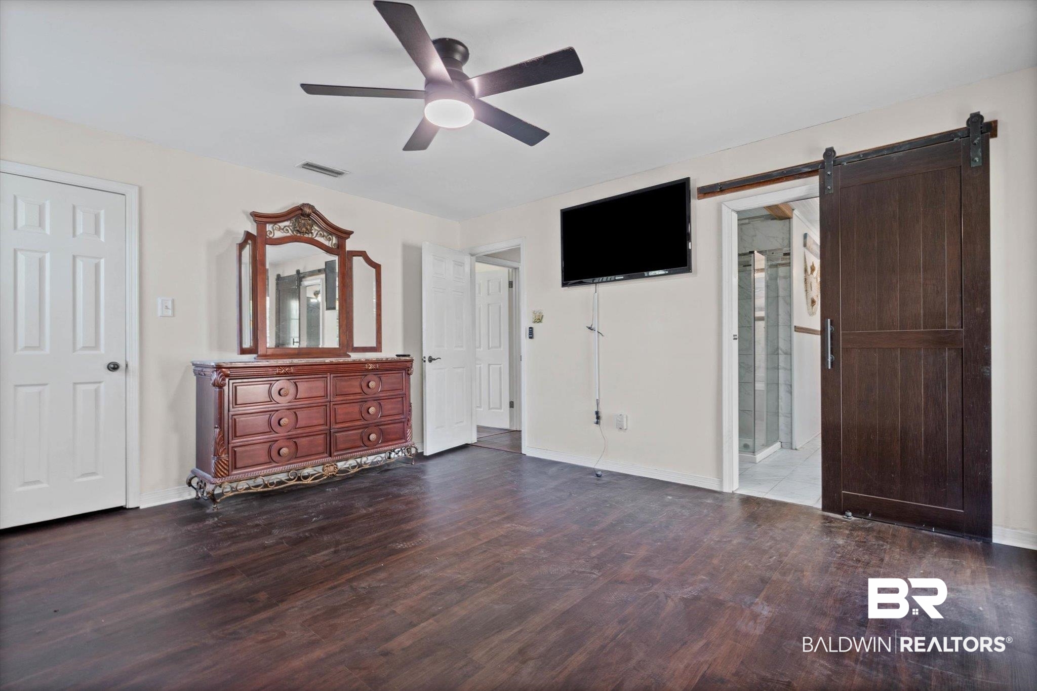 180 Creax Road Axis, AL 36505 - Photo 10 of 35 Unfurnished bedroom featuring dark wood-type flooring, a barn door, ceiling fan, and connected bathroom