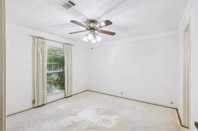 an empty room with windows and fan