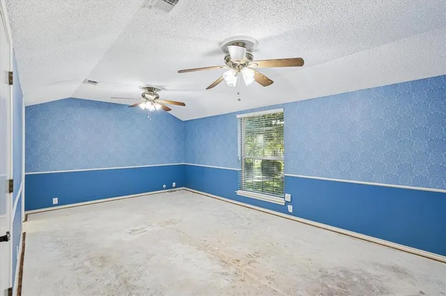 an empty room with windows and chandelier fan