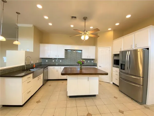 a large kitchen with kitchen island a stove a sink dishwasher a refrigerator and white cabinets with wooden floor
