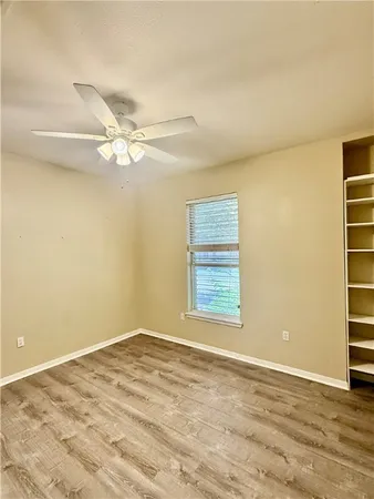 an empty room with a window and a ceiling fan