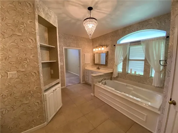 a spacious bathroom with a granite countertop sink a mirror and a bathtub