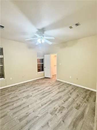 en empty room with wooden floor and fan