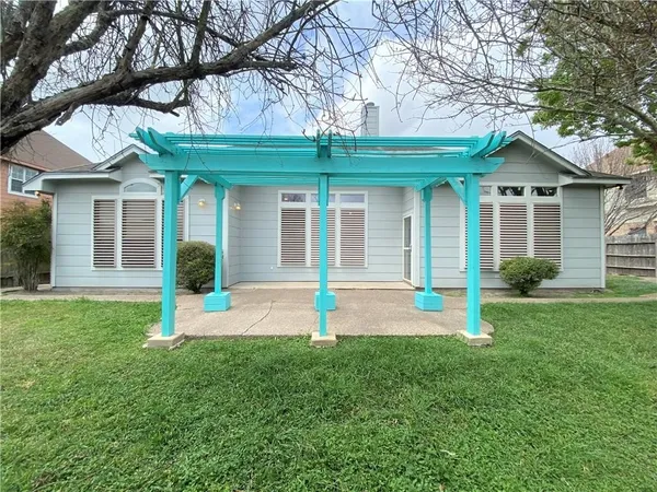 a front view of a house with plants and large tree