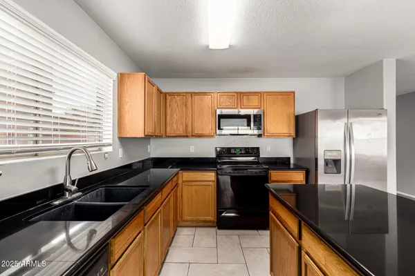 a kitchen with granite countertop stainless steel appliances a sink stove and refrigerator
