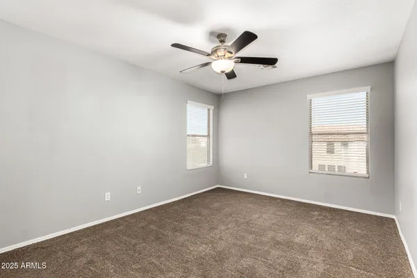 an empty room with windows and fan