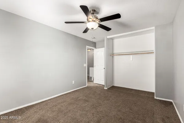 an empty room with closet and ceiling fan