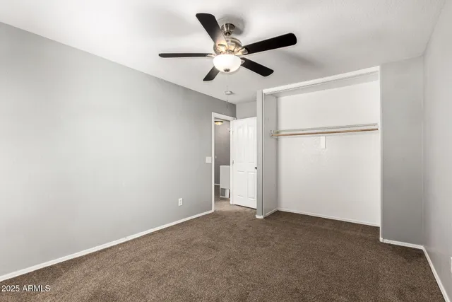 an empty room with closet and ceiling fan