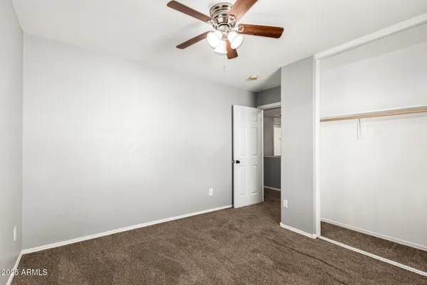 an empty room with closet and a chandelier fan