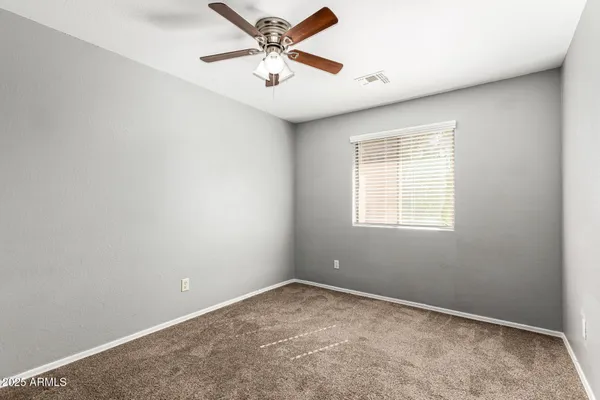 an empty room with a window and a fan