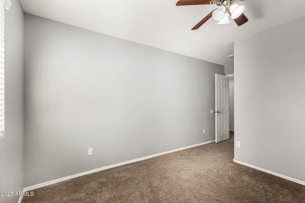 an empty room with a ceiling fan and carpet