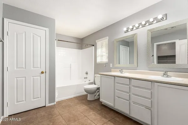 a spacious bathroom with a double vanity sink a large mirror and a bathtub