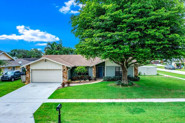a front view of a house with a garden and trees