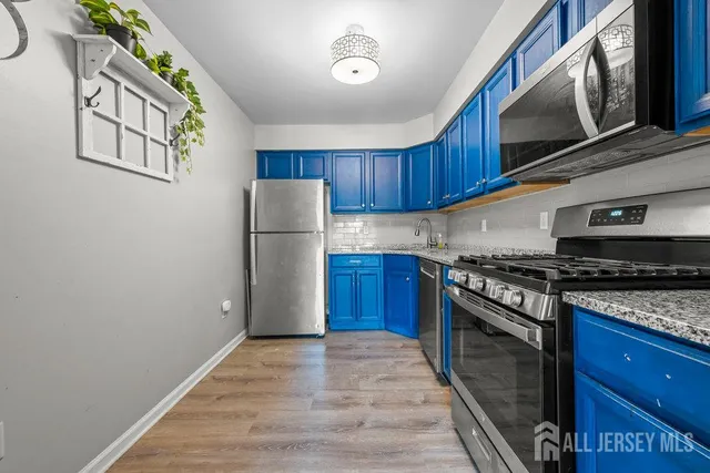 a kitchen with stainless steel appliances granite countertop a refrigerator a stove and a wooden floors