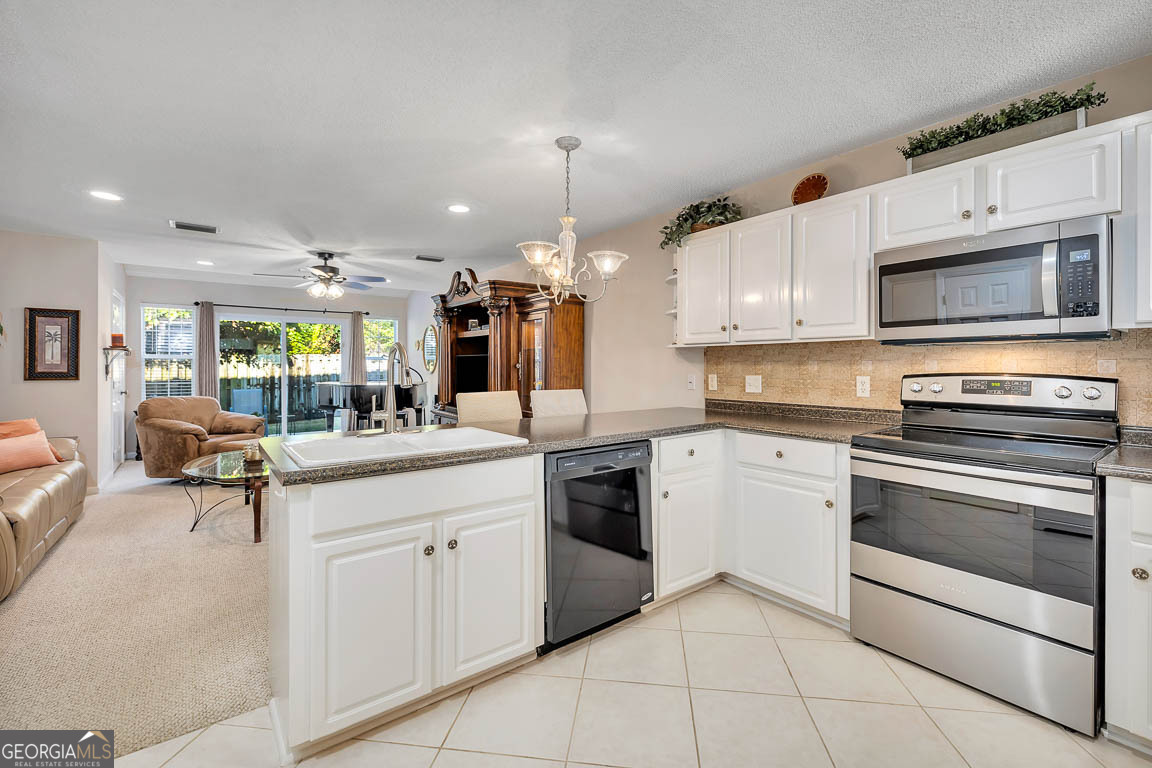 1000 Mallery Street, Unit D27 St. Simons, GA 31522 - Photo 3 of 34 a kitchen with stainless steel appliances kitchen island granite countertop a sink and cabinets